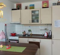 Küche in einer Einzimmerwohnung mit Holzboden und hellen Schränken.
