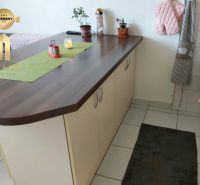Küchenzeile mit Insel in einer Einzimmerwohnung, weiße Fliesen und Dekorationen.