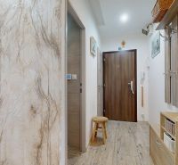 Der Flur in der 3-Zimmer-Wohnung hat einen Boden mit Holzdekor und hellem Mobiliar.