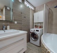 Badezimmer in einer 3-Zimmer-Wohnung mit Badewanne, Waschbecken und Waschmaschine.