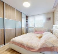 Schlafzimmer in einer 3-Zimmer-Wohnung mit Bett, Einbauschrank und Boden mit Holzdekor.