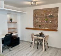 Ein Zimmer mit einer Ziegelwand, einem Tisch und einem Holzboden in einer Einzimmerwohnung.