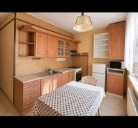 Die Küche in der 2-Zimmer-Wohnung hat einen Boden mit Holzdekor und eine gepunktete Tischdecke.
