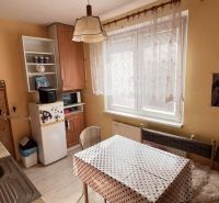 Küche in einer 2-Zimmer-Wohnung mit Esstisch, hohem Schrank und Fenster.