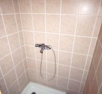 Duschkabine im Badezimmer mit Fliesen in sanften Farbtönen.