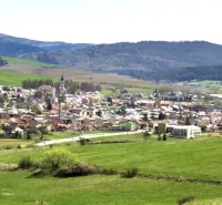 Ľubica, umgeben von landwirtschaftlichen und forstwirtschaftlichen Flächen mit Hügeln im Hintergrund.