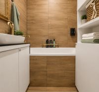 Badezimmer mit Fliesen in Holzoptik, weißen Schränken und Accessoires in einer 3-Zimmer-Wohnung.