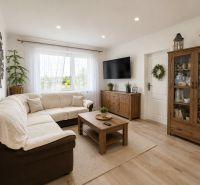 Wohnzimmer in einer 3-Zimmer-Wohnung mit einem bequemen Sofa und einem Boden in Holzoptik.
