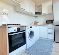 Küche in einer 2-Zimmer-Wohnung mit weißen Schränken und einem Boden in Holzoptik.
