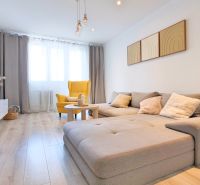 Wohnzimmer in einer 2-Zimmer-Wohnung mit Holzboden und bequemen Sitzgelegenheiten.