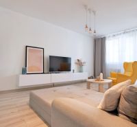 Wohnzimmer mit Sofa, gelbem Sessel und Holzboden in einer 2-Zimmer-Wohnung.