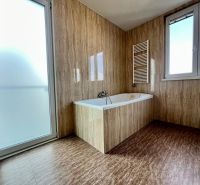 Badezimmer in einer 2-Zimmer-Wohnung mit Badewanne, Fenster und Glastüren.