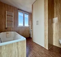 Badezimmer mit Badewanne und Holzboden in einer Zweizimmerwohnung.