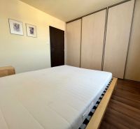 Schlafzimmer mit Doppelbett, Einbauschrank und Holzboden in einer Zweizimmerwohnung.