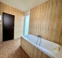 Badezimmer mit Badewanne und Fliesen in einer 2-Zimmer-Wohnung.