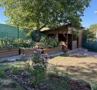 Gärten in Zvolen mit hölzernen Beeten und einem Pavillon, umgeben von Grün und Blumen.