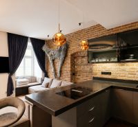Küche in einer 2-Zimmer-Wohnung mit Ziegelwand und dunklen Vorhängen.