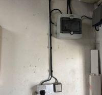 Elektroinstallation in der Garage mit einem Schrank und Kabeln an der Wand.