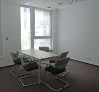 Büros mit Teppichboden, Konferenztisch, grüne Stühle, natürliches Licht.