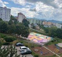 Blick auf einen bunten Spielplatz, einen Spielplatz und Plattenbauten in der Mateja Bela in Trenčín.