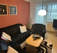 Wohnzimmer in einer 3-Zimmer-Wohnung mit Sofa, Tisch und Wanddekorationen.