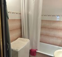 Badezimmer mit Badewanne, Waschmaschine mit Handtuch und Fliesen in einer 3-Zimmer-Wohnung.