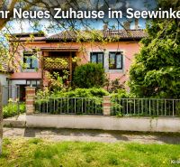 Ein Einfamilienhaus in Illmitz mit rosa Fassade und einem grünen Vorgarten voller Pflanzen.