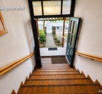 Eine Treppe in einem Einfamilienhaus mit Blick auf den Garten durch die offenen Türen.