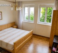 Schlafzimmer in einem Einfamilienhaus mit Holzboden, großem Fenster und Bett.