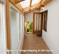 Veranda mit Glasdach und Treppe in einem Einfamilienhaus.