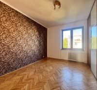 Ein Zimmer in einer 4-Zimmer-Wohnung mit einem Boden in Holzoptik und gemusterten Tapeten.