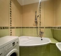 Badezimmer in einer 4-Zimmer-Wohnung mit Badewanne und Waschmaschine, grün-cremefarbene Fliesen.