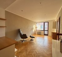 Wohnzimmer in einer Vierzimmerwohnung mit Holzboden und einem bequemen Sessel.