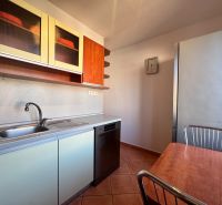 Küche einer 4-Zimmer-Wohnung mit Küchentisch, Geschirrspüler und Schränken mit Holzdekor.