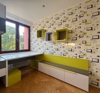 Ein Zimmer in einer 4-Zimmer-Wohnung mit geometrischer Tapete, Möbeln und einem Boden in Holzoptik.