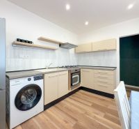 Küche in einer 2-Zimmer-Wohnung mit Holzboden, hellen Möbeln und Geräten.