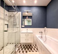 Badezimmer in einer 2-Zimmer-Wohnung mit Duschkabine, Badewanne und weißen Fliesen.