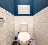 Badezimmer in einer 2-Zimmer-Wohnung mit weißen Fliesen und dunkelblauen Wänden.