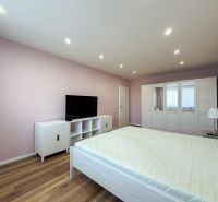 Schlafzimmer in einer 2-Zimmer-Wohnung mit Holzboden und weißen Möbeln.
