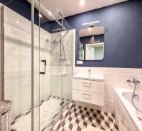 Badezimmer in einer 2-Zimmer-Wohnung mit Badewanne, Dusche und Designerfliesen.