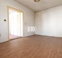 Ein Zimmer in einem Einfamilienhaus mit weißen Wänden und einem Boden in Holzoptik.