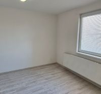 Ein Zimmer in einer 2-Zimmer-Wohnung mit weißen Wänden und einem Boden in Holzoptik.