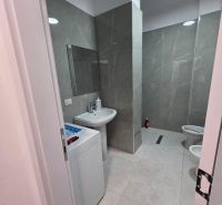 Badezimmer in einer 2-Zimmer-Wohnung mit Duschkabine, Waschmaschine und Keramikfliesen.