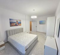 Helles Schlafzimmer in einer 2-Zimmer-Wohnung mit Kunstgemälden und weißen Möbeln.