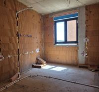 Unvollendetes Zimmer in einer 3-Zimmer-Wohnung mit freiliegenden Ziegelwänden und einem Fenster.