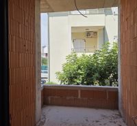 Ein unvollendeter Balkon in einer 3-Zimmer-Wohnung mit Blick auf Grünflächen und ein Nachbargebäude.