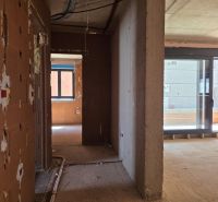 Unvollendetes Interieur einer 3-Zimmer-Wohnung mit großen Glastüren und Mauerwerk.