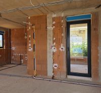 Unvollendete 3-Zimmer-Wohnung mit Ziegelwänden und Elektroinstallation, die zur Montage vorbereitet ist.