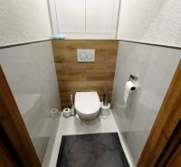 Toilette mit Holzboden und weißen Fliesen in einer 3-Zimmer-Wohnung.