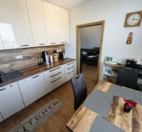 Küche mit weißen Schränken und Holzboden in einer 3-Zimmer-Wohnung.